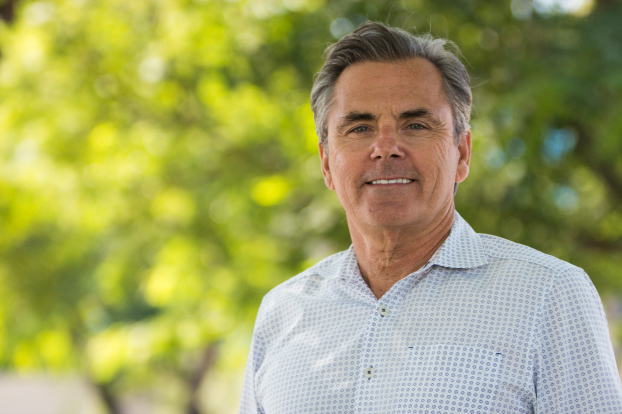 Outdoor professional headshot — soft green bokeh